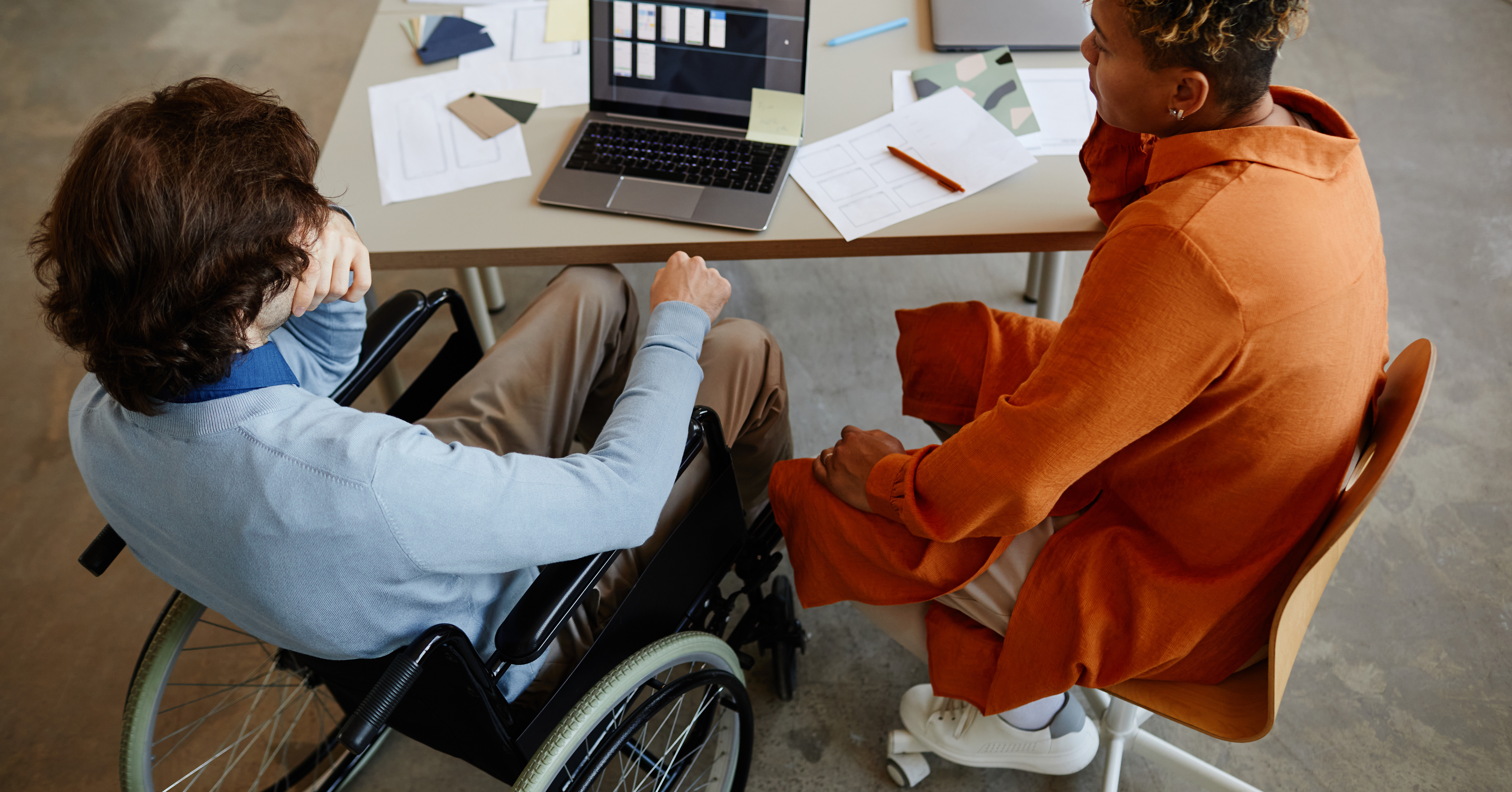 top-view-young-man-with-disability-talking-colleague-manager-while-working-it-developmen